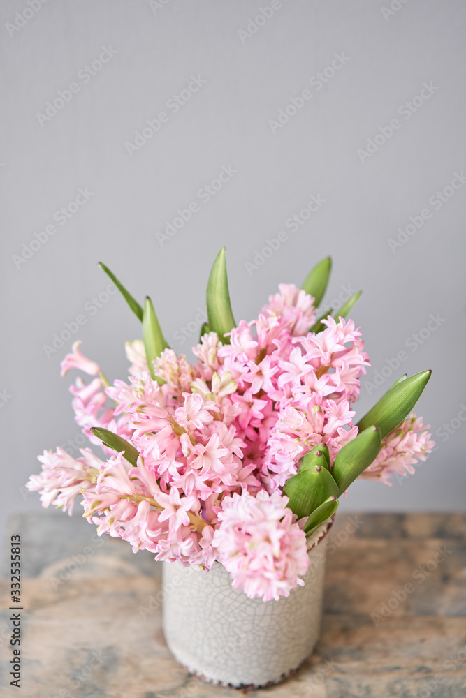 Bouquets of pink hyacinths in vase on wooden table. Spring flowers from Dutch gardener. Concept of a florist in a flower shop. Wallpaper. Bouquets of pink hyacinths in vase on wooden table. Spring flowers from Dutch gardener. Concept of a florist in a flower shop. Wallpaper.