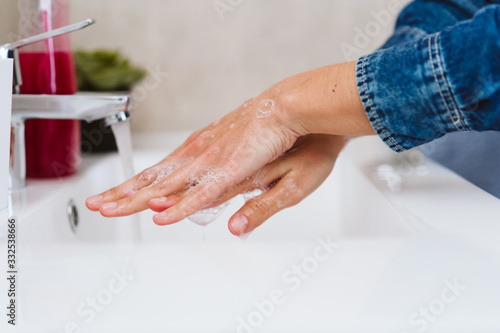 unrecognizable woman washing hands on a sink with soap. Coronavirus covid-19 concept