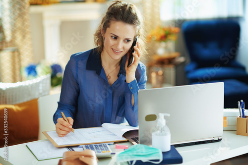 woman in modern house in sunny day talking on phone and working