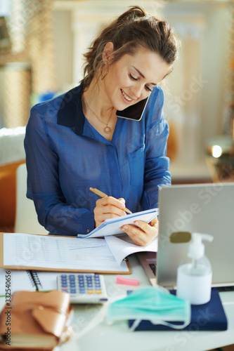 woman at modern home in sunny day talking on phone and working