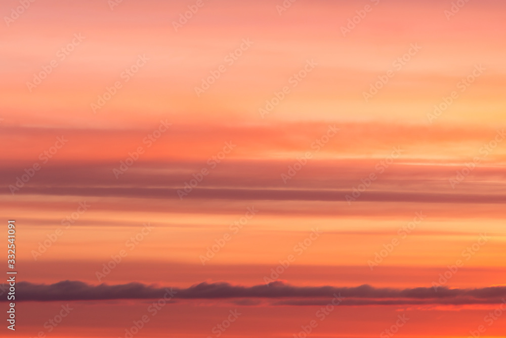 Bright soft sunrise, sunset orange yellow red sky with clouds background texture