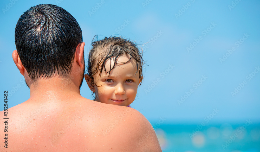 daddy at the beach wrapping his little girl in a towel after bath on the sea