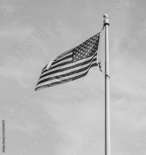 Wallpaper Mural Close up black and white image of the American flag on a flag pole blowing in the wind against a grey sky Torontodigital.ca