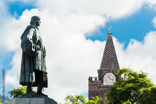 A statue of Joao Goncalves Zarco, the founder of Madeira Island, stands on Arriaga avenue and looking to the clock of Se cathedral in Funchal, Madeira Island, Portugal. photo
