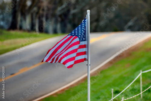 An American flag waving in the breeze beside a highway.