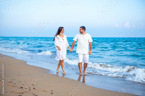 Couple of lovers just married, honeymoon. Elegant and attractive happy family man and woman walking at sea coast. Young wife and husband in love
