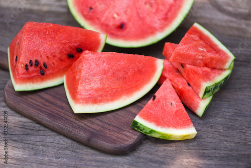 Sliced watermelon on wooden cutting board background - Close up fresh watermelon pieces tropical summer fruit