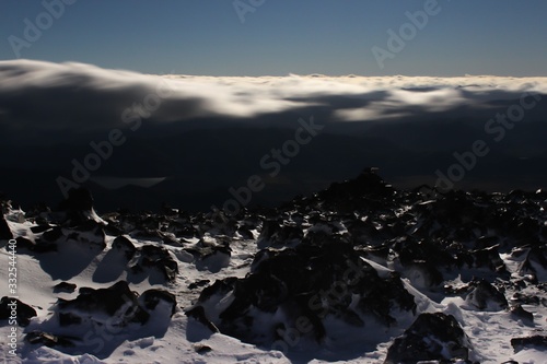 View from the snowy summit: mountains top above the clouds. Cloud bed in the Andes in the evening. Neuquen, Argentina.