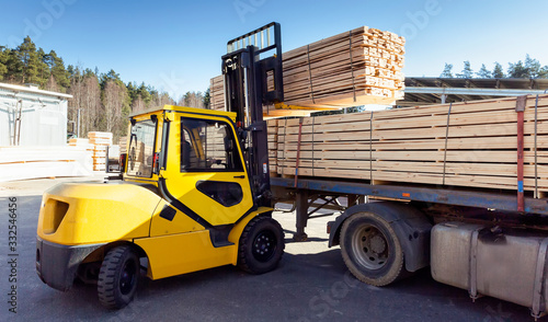 The machine loads the boards, lumber from the finished goods warehouse onto the truck photo
