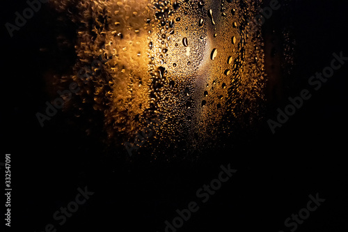 Rain drops on the glass on a background of a night blurred light