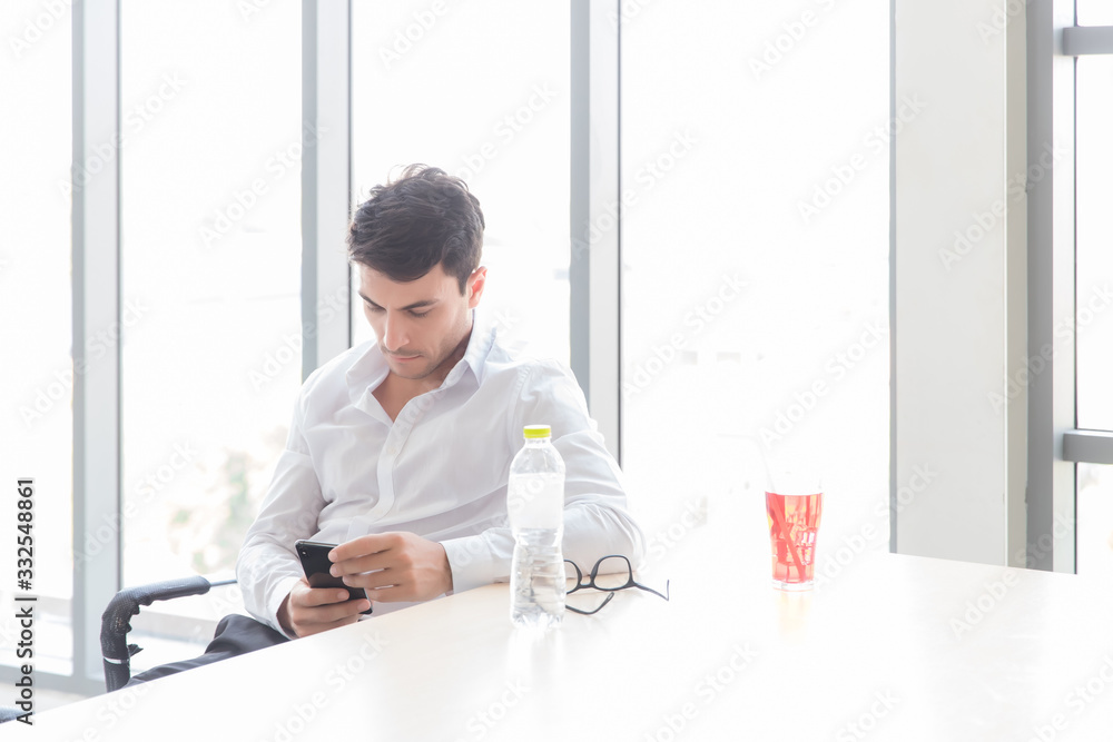 A young businessman is checking his return flight on his mobile phone because of the spread of the Covid-19 virus, causing the airline to stop flying on many flights.