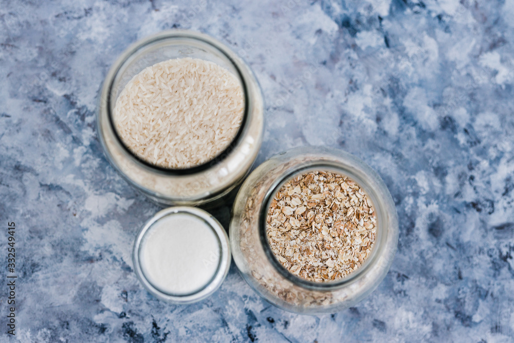 non-perishable food ingredients for vegan pantry, glass jars with oats flour and rice non-perishable food ingredients for vegan pantry, glass jars with oats flour and rice