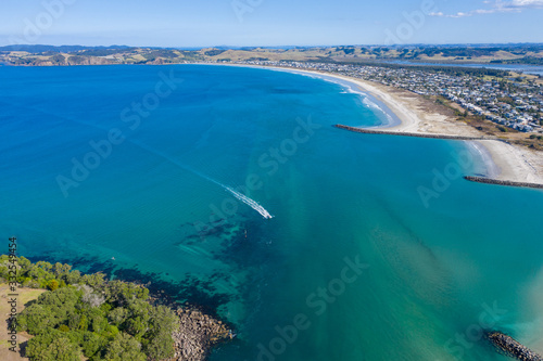 Aerial View from the Fast Boat in the Sea, Green Trees and Waves of Omaha in New Zealand - Auckland Area 