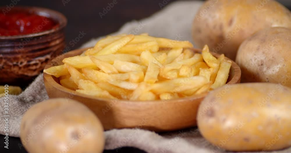 French fries in a plate on the old bag with fresh potatoes and tomato sauce. French fries in a plate on the old bag with fresh potatoes and tomato sauce.