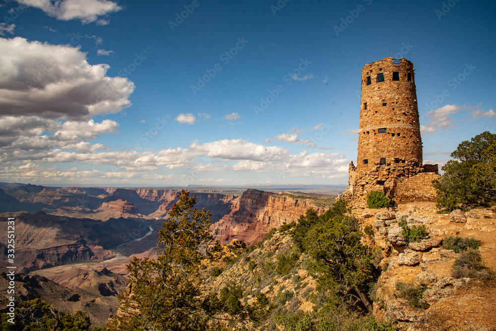 The Grand Canyon in Arizona with watch tower in view with blue sky and clouds in background and deep canyon below perfect, tourism area of United States of America. The Grand Canyon in Arizona with watch tower in view with blue sky and clouds in background and deep canyon below perfect, tourism area of United States of America.