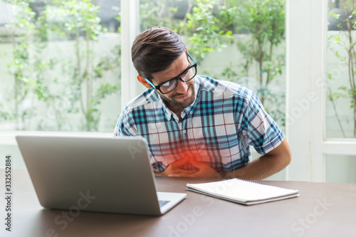 Young businessman stomachache from Working with Laptop, Sitting in home office.