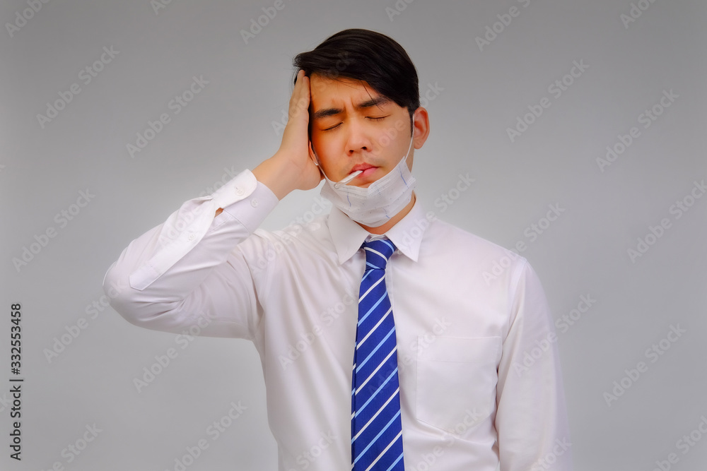 Businessman wears medical masks with fever checking his temperature is a viral disease contagious feel pain in their head on gray background, corona virus concept, covid19 concept, medical concept Businessman wears medical masks with fever checking his temperature is a viral disease contagious feel pain in their head on gray background, corona virus concept, covid19 concept, medical concept