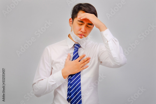 Businessman wears medical masks with fever checking his temperature is a viral disease contagious feel pain in their head on gray background, corona virus concept, covid19 concept, medical concept photo