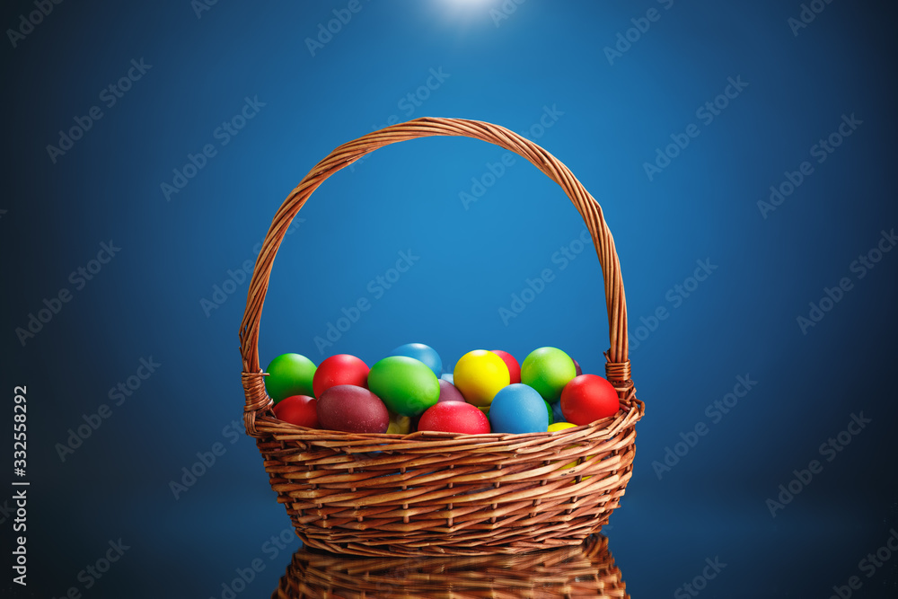 Easter color eggs in festive gift basket, blue background Easter color eggs in festive gift basket, blue background