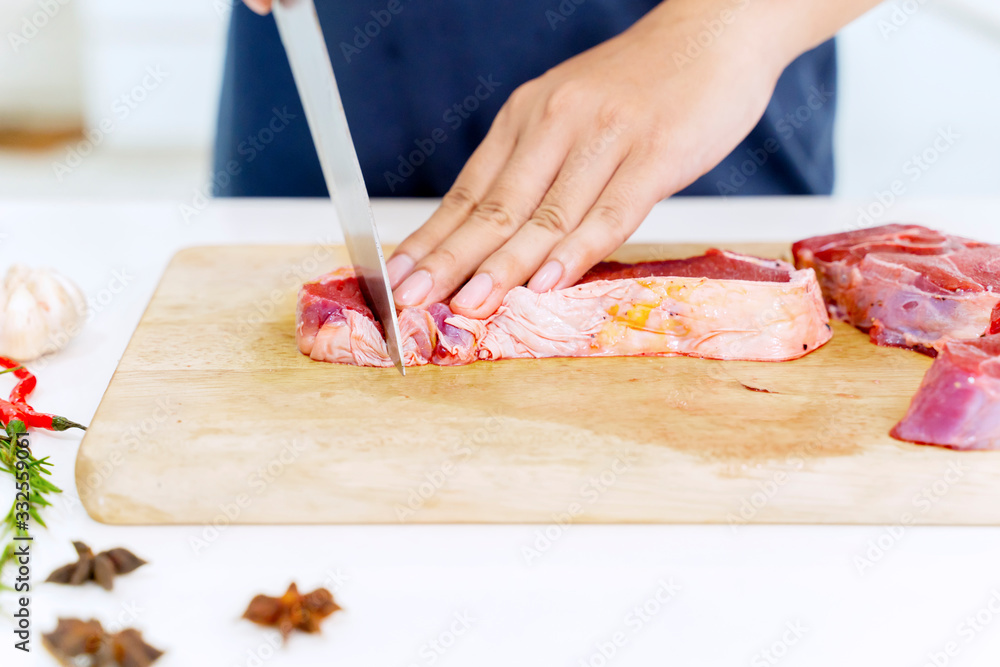 Closeup of hand cutting red meat near condiments