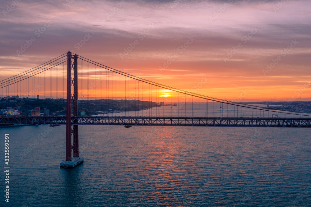 Lisbon, Portugal. Aerial view of the 25 de Abril Bridge (Ponte 25 de Abril, 25th of April Bridge) at sunset. It is often compared to the Golden Gate Bridge in San Francisco, US. Lisbon, Portugal. Aerial view of the 25 de Abril Bridge (Ponte 25 de Abril, 25th of April Bridge) at sunset. It is often compared to the Golden Gate Bridge in San Francisco, US.