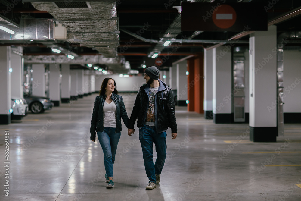 happy couple walking in the underground parking of a shopping center