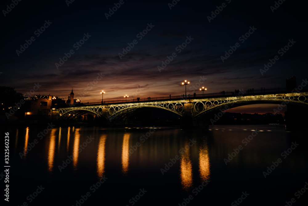 Sunset over Guadalquivir river.Triana neighborhood with bridge of Isabel II. Beautiful sunset on the bank of Canal de Alfonso-XIII,Sevilla,Andalucia,Spain