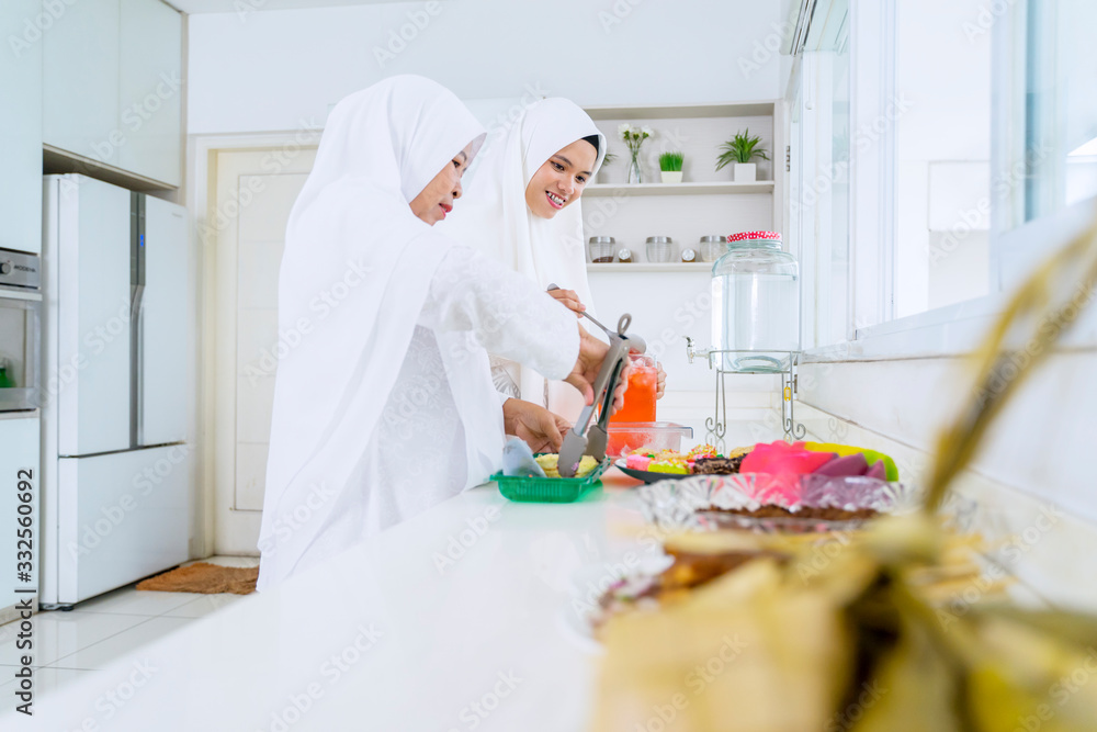 Mother and woman serving food and beverage in kitchen