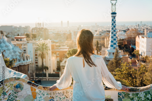 Young female tourist spending vacation in Barcelona,Catalonia,Spain.Traveling to Europe,visiting Parc Guell UNESCO site famous historical landmarks.Panoramic view on entrance.Best sunrise in Barcelona photo
