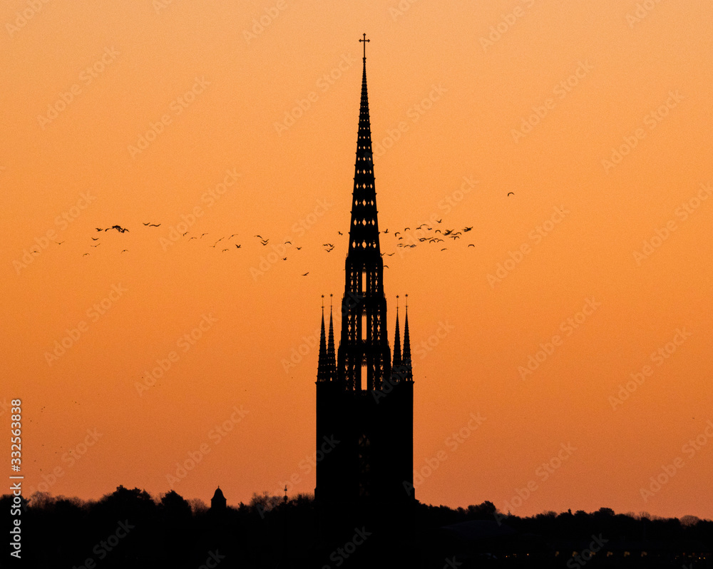 Morning skyline at sunrise over the old town district Gamla Stan in orange light sky with profiles of houses and churches. Morning skyline at sunrise over the old town district Gamla Stan in orange light sky with profiles of houses and churches.