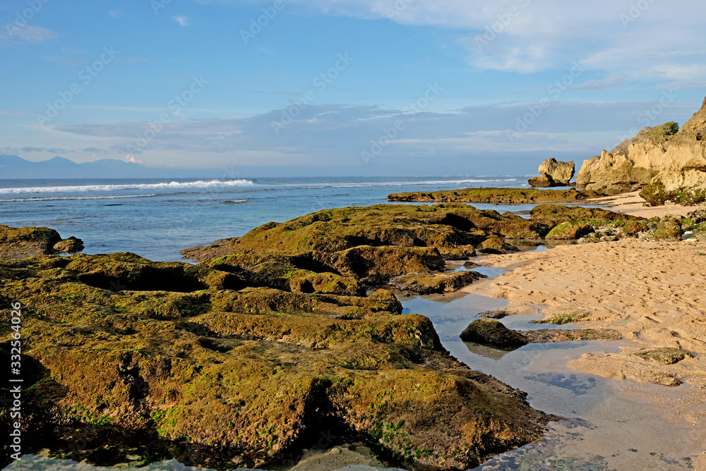 Beautiful coastline with rocks in the foreground and volcanic mountains at the background. A perfect spot for surfers all over the world in Uluwatu, Bali, Indonesia