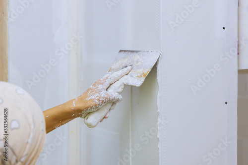 Hand with a spatula plaster on a wall