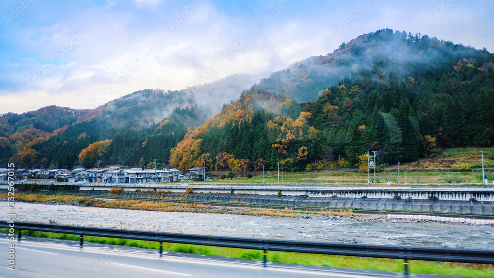 Scenic landscape view of beautiful natural environment around the village in fall with river mountain fog and blue sky background at countryside of Japan.