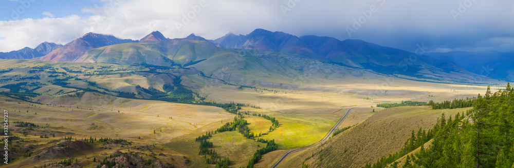 Mountain valley, panoramic view. Rural landscape, cloudy weather, thunder sky. Traveling in the mountains.