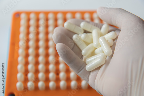 White pill capsules in white medical gloves photo