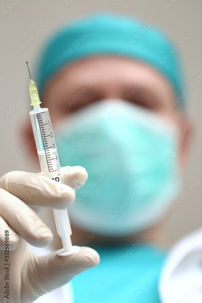Coronavirus concept. A doctor in uniform and in a protective antiviral mask with a syringe.Medicine and health concept. Vaccination against the virus. Virus protection.Prevention of colds and flu. Coronavirus concept. A doctor in uniform and in a protective antiviral mask with a syringe.Medicine and health concept. Vaccination against the virus. Virus protection.Prevention of colds and flu.
