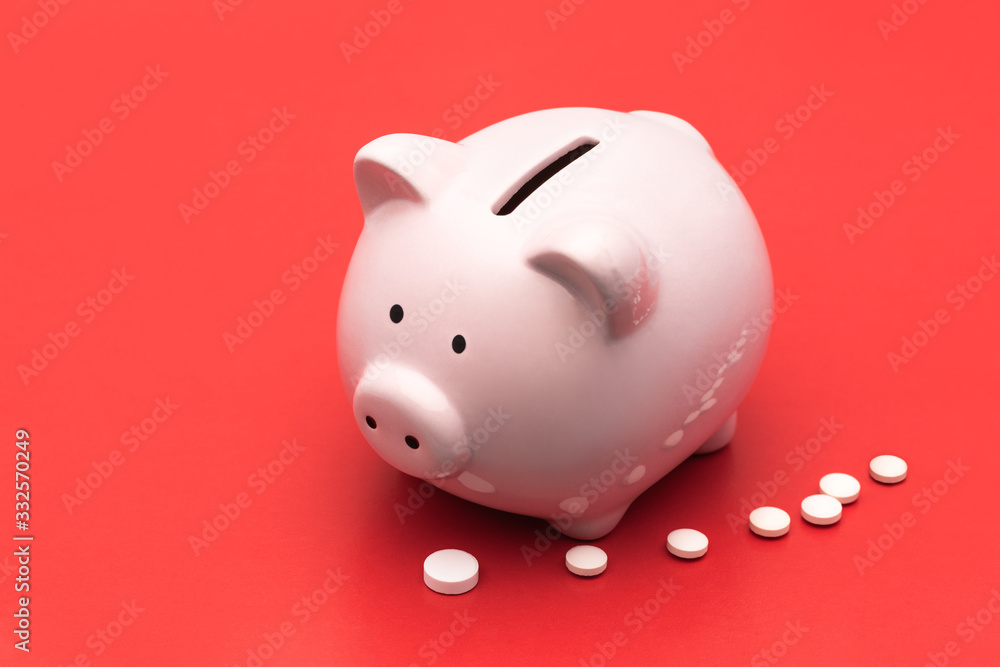 Pink piggy Bank stands  on a bright red background , next to them are white  tablets in the form of a strip. Chinese Coronavirus , 2019-nCoV