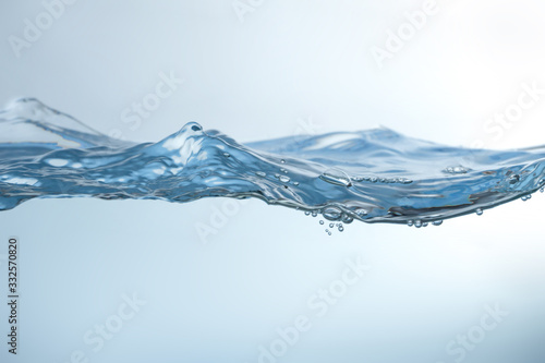 Water splash on blue background. Aqua flowing in waves and creating bubbles. Drops on the water surface feel fresh and clean.