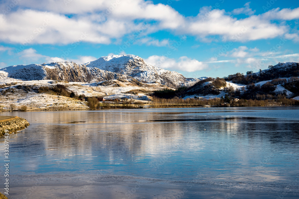 A scenic landscape view of mountains covered by snow from Edlandsvatnet lake, Algard, Norway, February 2018