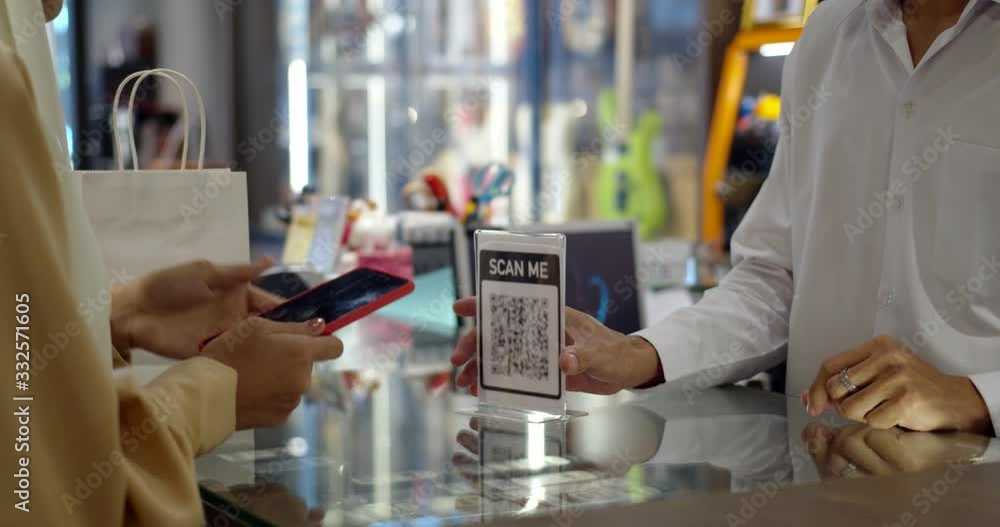 Young woman paying by scanning QR Code with smartphone