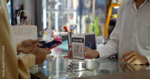 Young woman paying by scanning QR Code with smartphone