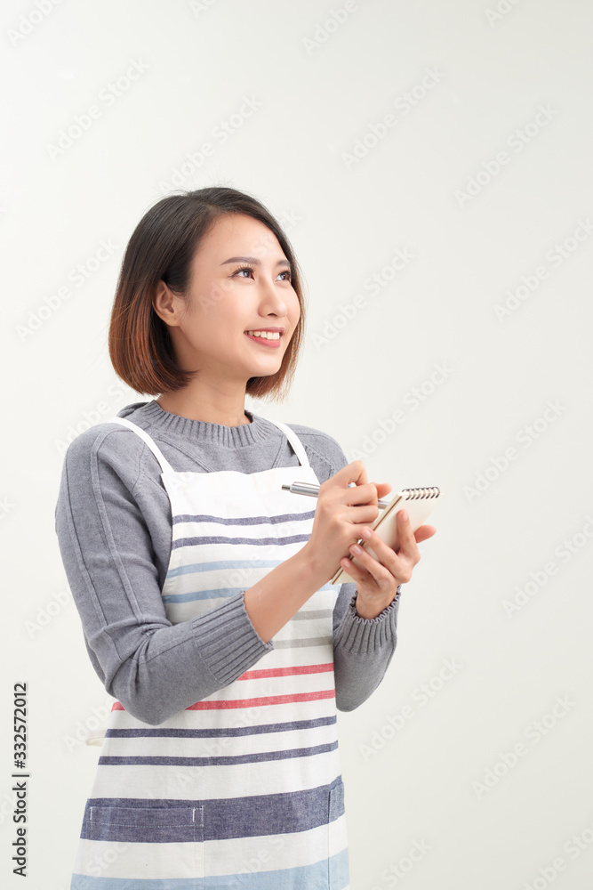 Head shot portrait of smiling waitress wearing black apron ready to take customer order, attractive woman with notebook and pen in hands looking at camera Head shot portrait of smiling waitress wearing black apron ready to take customer order, attractive woman with notebook and pen in hands looking at camera