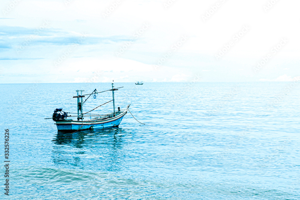 Small fishing boat floating in blue sea with blue sky, Thailand fishing boat or fisherman boat or ship on Sam Roi Yod beach Prachuap Khiri Khan Thailand with blue sky and cloud and blue sea