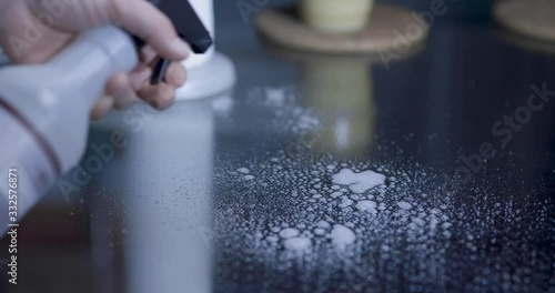 Spraying the table with the cleaner product. Wipe down the table with a soft cloth until is clean.