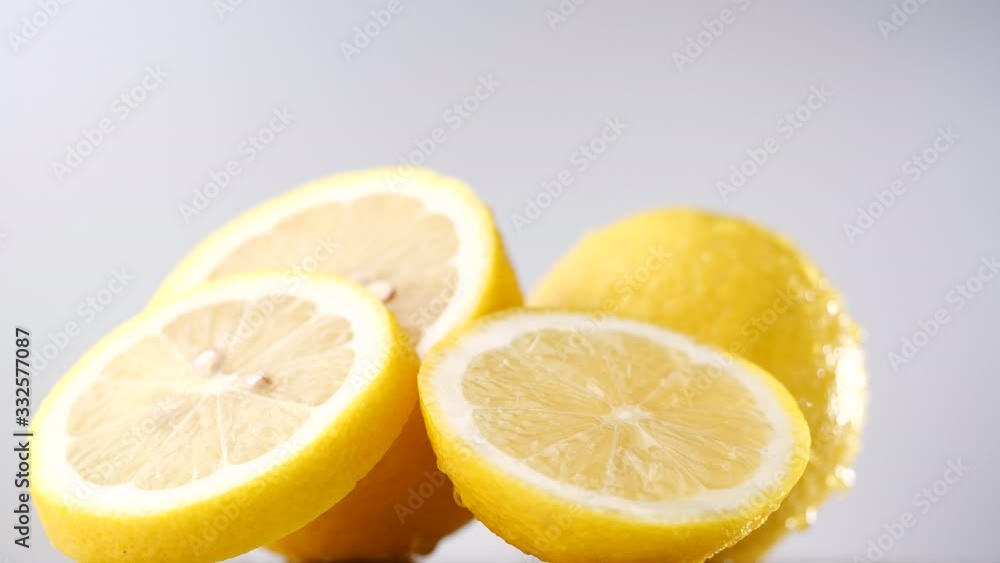 Fresh lemon slice rotation in slow motion on gray background, Lemon with dripping water