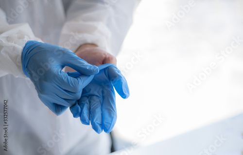 Human hands taking off blue disposable gloves.