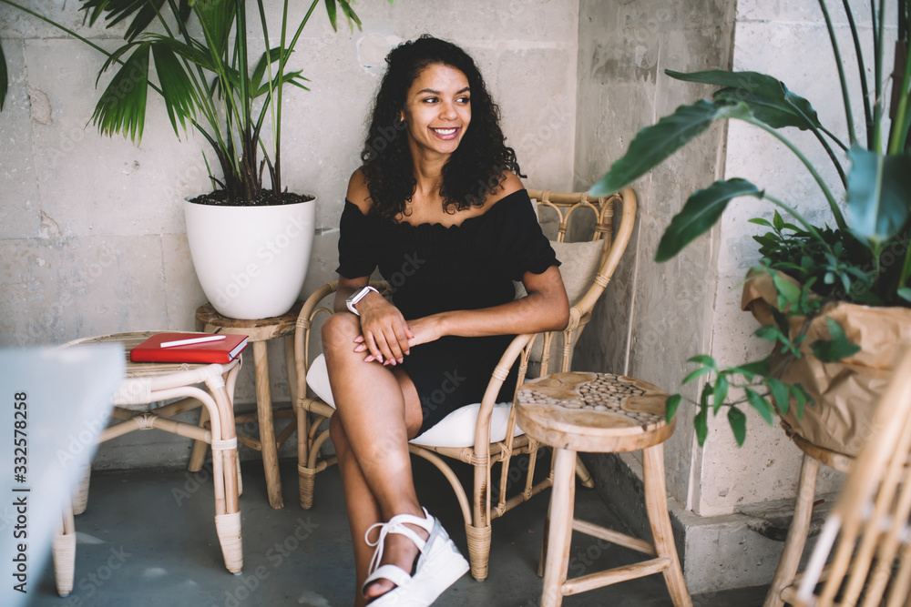 Smiling attractive dark skinned woman blogger enjoying spending free time in modern designed interior with decorations, positive african american hipster girl recreating indoors on leisure Smiling attractive dark skinned woman blogger enjoying spending free time in modern designed interior with decorations, positive african american hipster girl recreating indoors on leisure