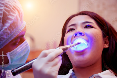 Young man dentist who treats teeth of young woman patient.