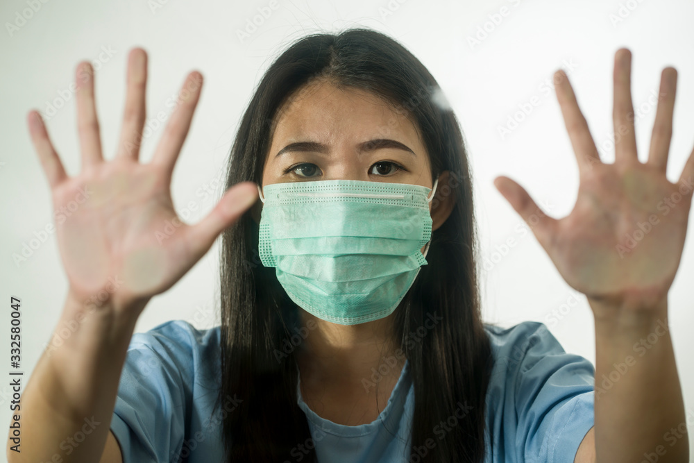 covid-19 pandemic - young scared and frightened Asian Chinese woman in medical mask isolated suffering lockdown and quarantine during contagious virus outbreak