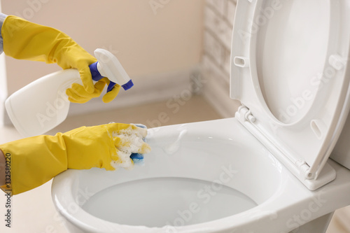 Woman cleaning toilet bowl in bathroom